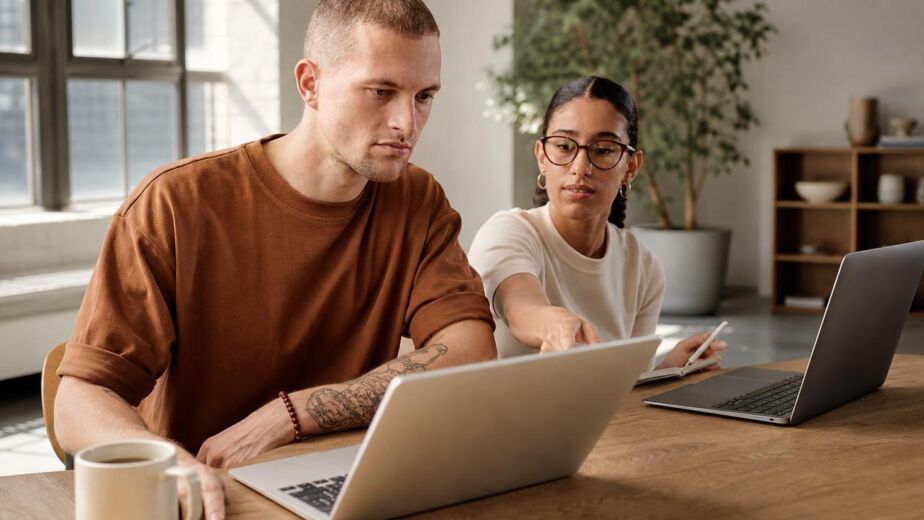 Two colleagues collaborating at laptops